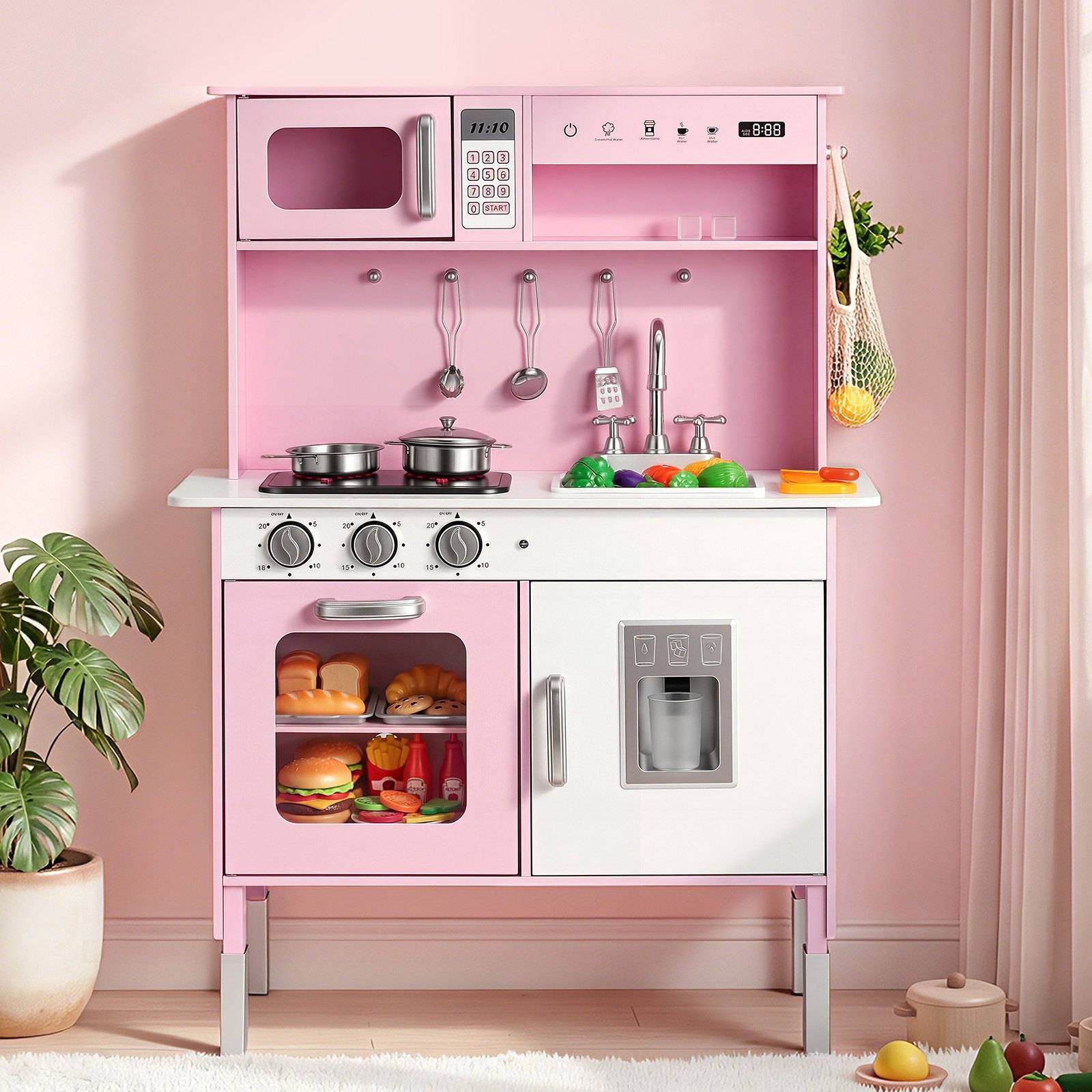 Rosa Spielküche mit Spielmikrowelle, Herd, Spüle, Ofen und Kühlschrank, plus Spielessen und Utensilien in einem Raum mit einer Topfpflanze.