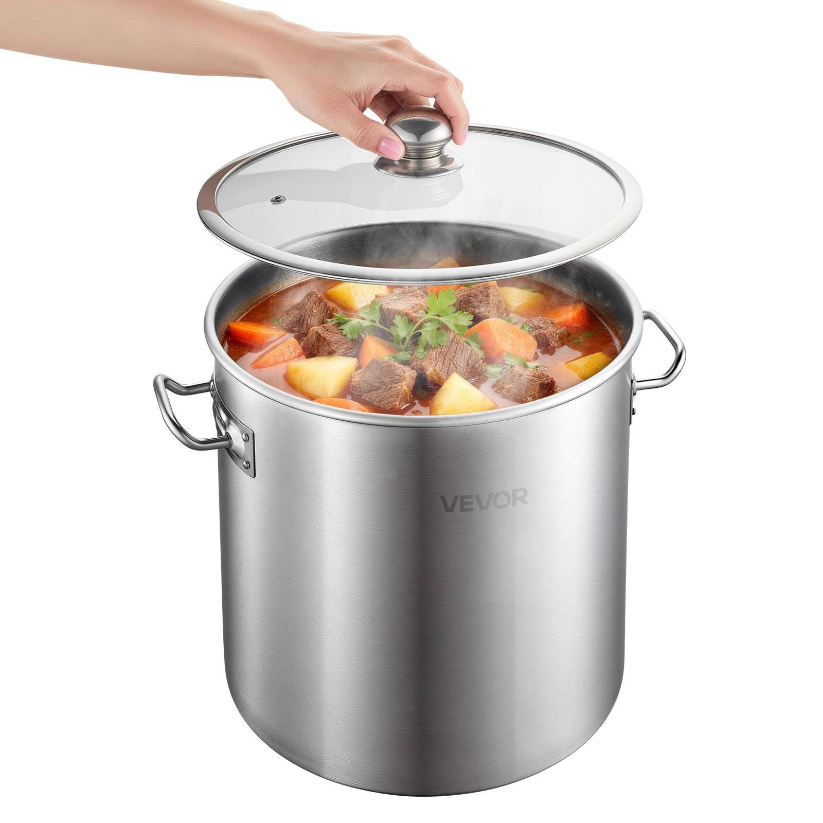 Hand hebt den Deckel eines aus Edelstahl gefertigten Suppentopfs mit Seitengriffen an, aus dem dampfende Rind- und Gemüsesuppe aufsteigt.