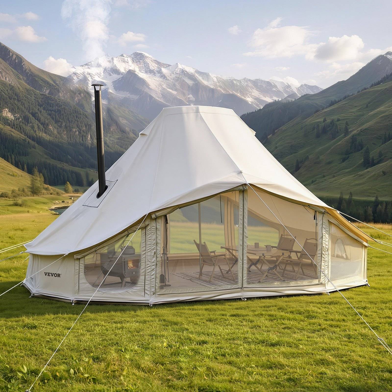 Großes weißes Glamping-Zelt mit Ofen und klaren Fenstern auf einer grünen Bergwiese mit Stühlen innen und schneebedeckten Gipfeln im Hintergrund.
