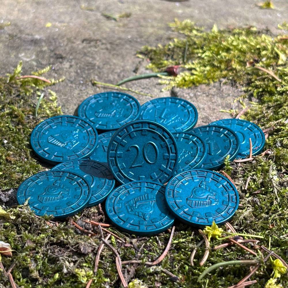 Ein Haufen blauer runder Spielsteine oder Spielplättchen mit der Markierung „20" liegt auf moosigem Untergrund im Freien.