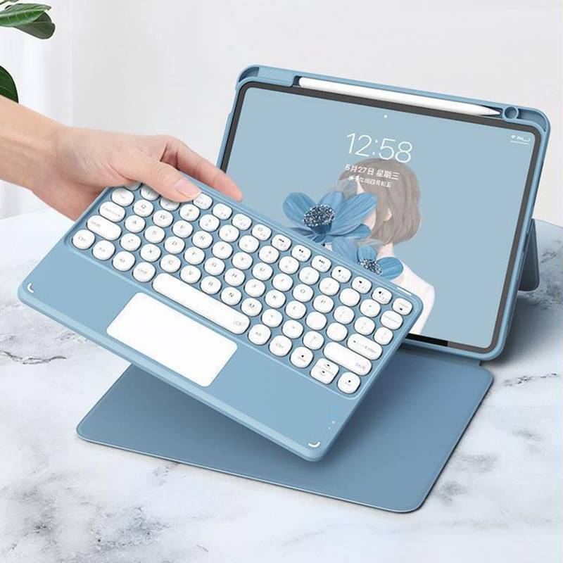 Hand hält ein blaues kabelloses Tastaturetui vor einem Tablet-Ständer mit passendem blauem Bezug auf einer Marmorflache.