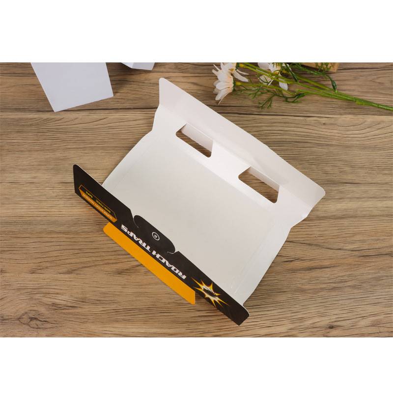 Offene weiße Kartongeschenkbox mit schwarzem und orangefarbenem Vorderlappen auf einem Holztisch, teilweise aufgeklappt gezeigt.