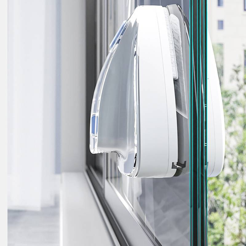 Nahaufnahme eines weißen, fenstermontierten Reinigungsgeräts mit einem durchsichtigen Saug- oder Schrubbpad, das an Glas befestigt ist.