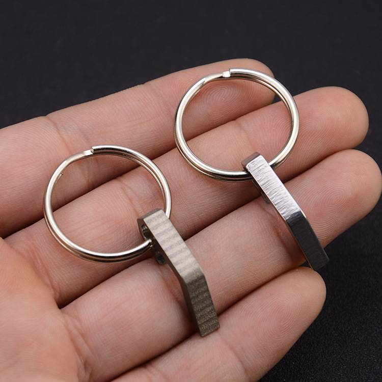 Zwei silberne Metallschlüsselanhänger-Ringe mit kurzen rechteckigen Griffen, die in der Handfläche einer Person vor dunklem Hintergrund ruhen.