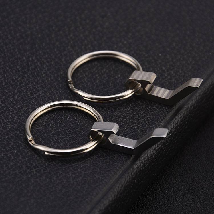 Zwei silberne Schlüsselringclips auf einer schwarzen, lederstrukturierten Oberfläche, einer über dem anderen, in Großaufnahme gezeigt.