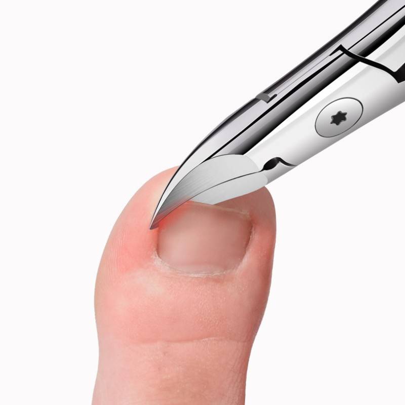 Nahaufnahme eines Fußnagels, der mit silbernen Nagelzangen gegen einen weißen Hintergrund geschnitten wird.