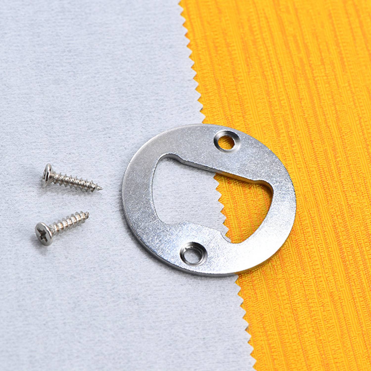 Ein Flaschenöffner-Ring aus Metall zur Wandmontage mit zwei Schrauben auf einem weiß und orange strukturierten Hintergrund.