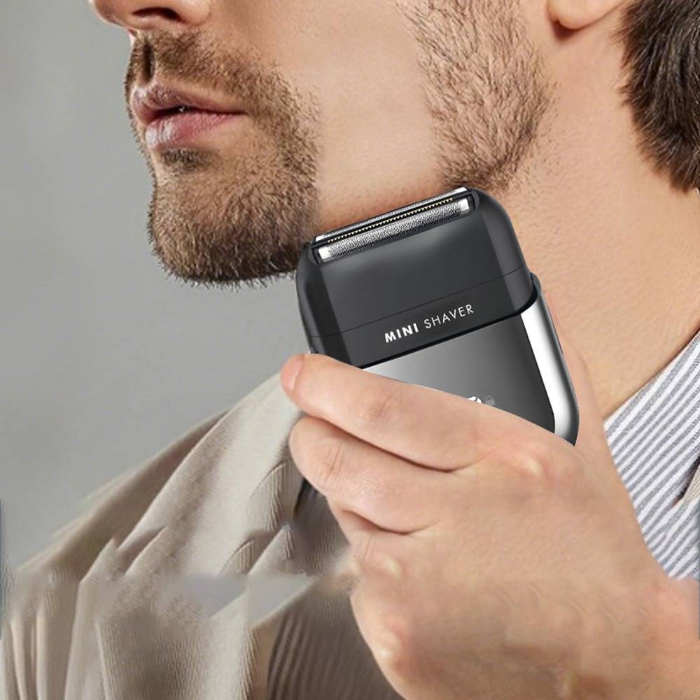 Ein Mann rasiert seinen Bart mit einem kompakten elektrischen „MINI SHAVER