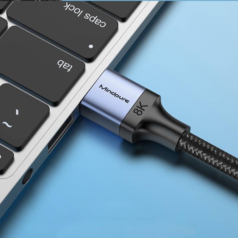 Nahaufnahme eines Laptops mit angeschlossenem USB-C-Kabel, das einen geflochtenen Stecker mit der Beschriftung "Mindpure"" und ""8K"" auf blauem Hintergrund zeigt.