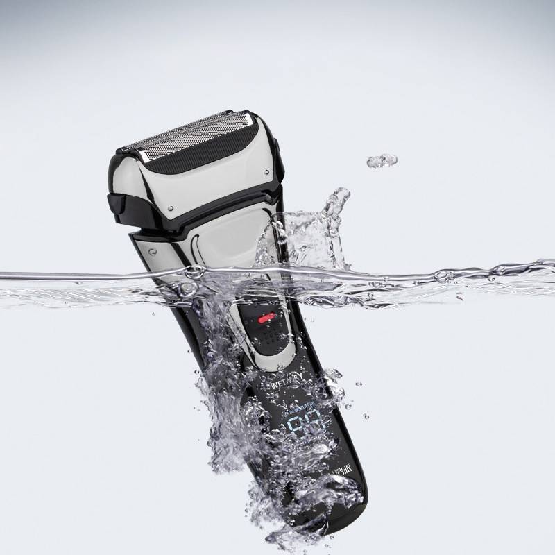 Elektrischer Rasierer teilweise ins Wasser getaucht, mit Spritzern, die darauf hindeuten, dass er wasserdicht ist.