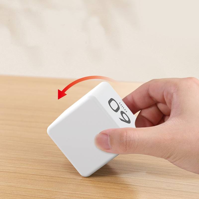 Hand, die einen weißen quadratischen Würfel auf einer Holzoberfläche neigt, mit einem roten Pfeil, der die Rotation anzeigt.
