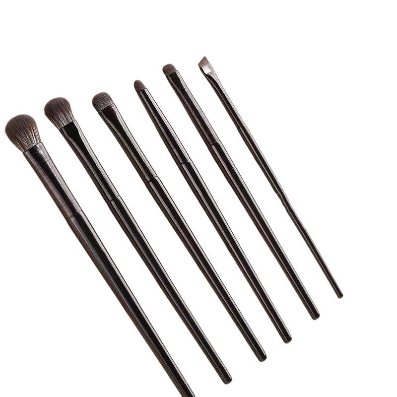 Fünf Makeup-Pinsel mit schwarzen Griffen und unterschiedlichen Borsten­formen diagonal auf weißem Hintergrund angeordnet.