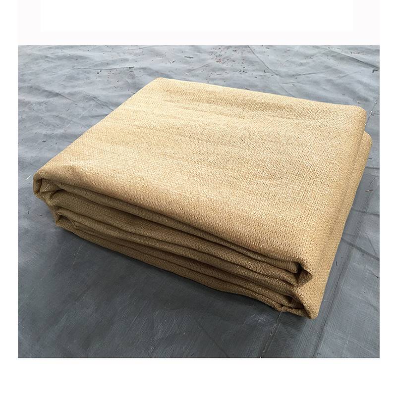 Gefalteter beiger Stoff oder eine beige Plane, gestapelt auf einer grauen Oberfläche.