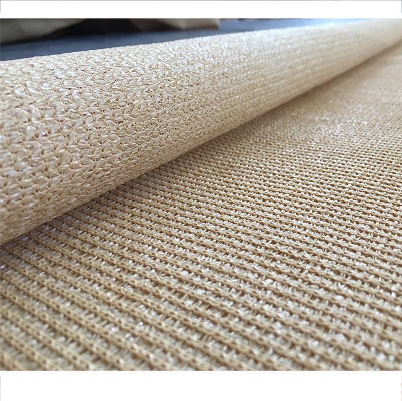 Nahaufnahme eines aufgerollten beigen gewebten Stoffs oder einer Matte, die seine strukturierte Oberfläche und die geschichtete Kante zeigt.