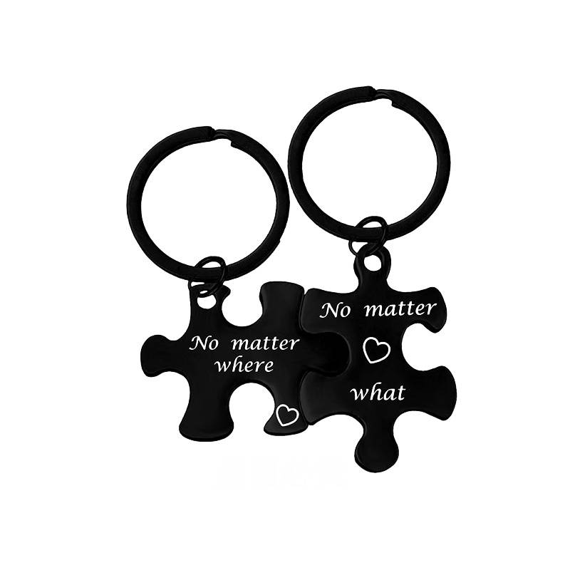 Zwei schwarze Puzzle-Anhänger verbunden durch Ringe, bedruckt mit „Egal wo