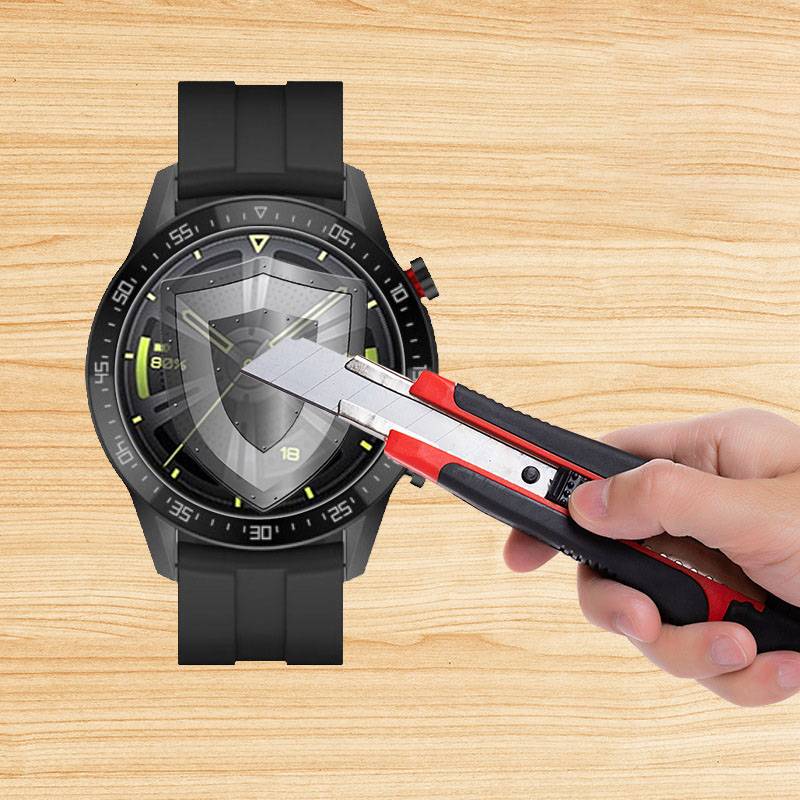 Eine Hand, die ein Universalmesser hält, schneidet eine transparente Schutzfolie auf einem schwarzen Uhrengehäuse ab und zeigt die Installation eines Displayschutzes.