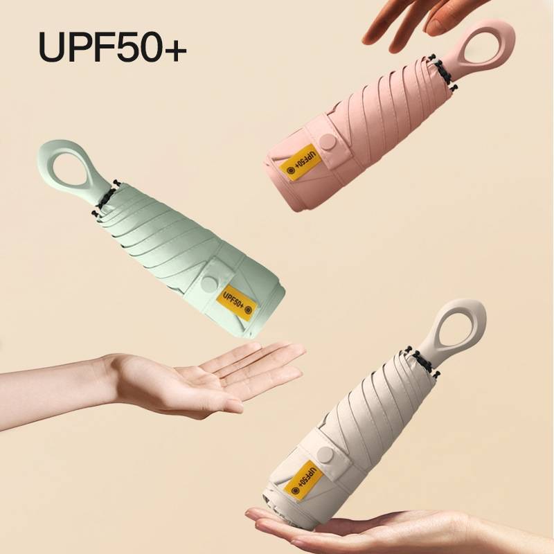 Drei kompakte, faltbare Regenschirme mit der Bezeichnung UPF50+ schweben über Händen, dargestellt in Pink, Mint und Beige auf einem einfachen Hintergrund.
