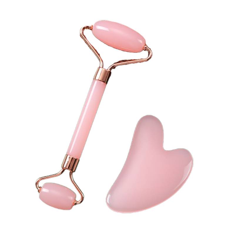 Rosa Gesichtsmassageroller mit herzförmigem Gua-Sha-Stein auf weißem Hintergrund.