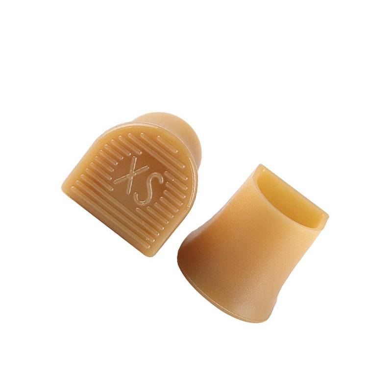 Zwei beige Silikon-Fingerschützer oder Daumenauflagen auf weißem Hintergrund, einer mit strukturierter Griffoberfläche und 'S'-Markierung.
