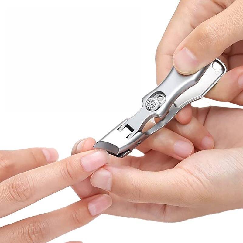 Hände, die einen Metall-Nagelknipser verwenden, um einen Fingernagel vor einem einfachen weißen Hintergrund zu schneiden.