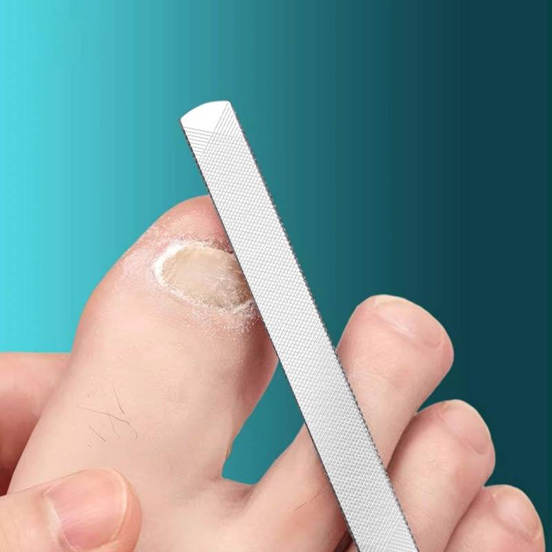 Nahaufnahme eines Fußes mit einer Nagelfeile, die einen verdickten, verfärbten Zehennagel formt, was auf häusliche Fußpflege oder Behandlung hindeutet.
