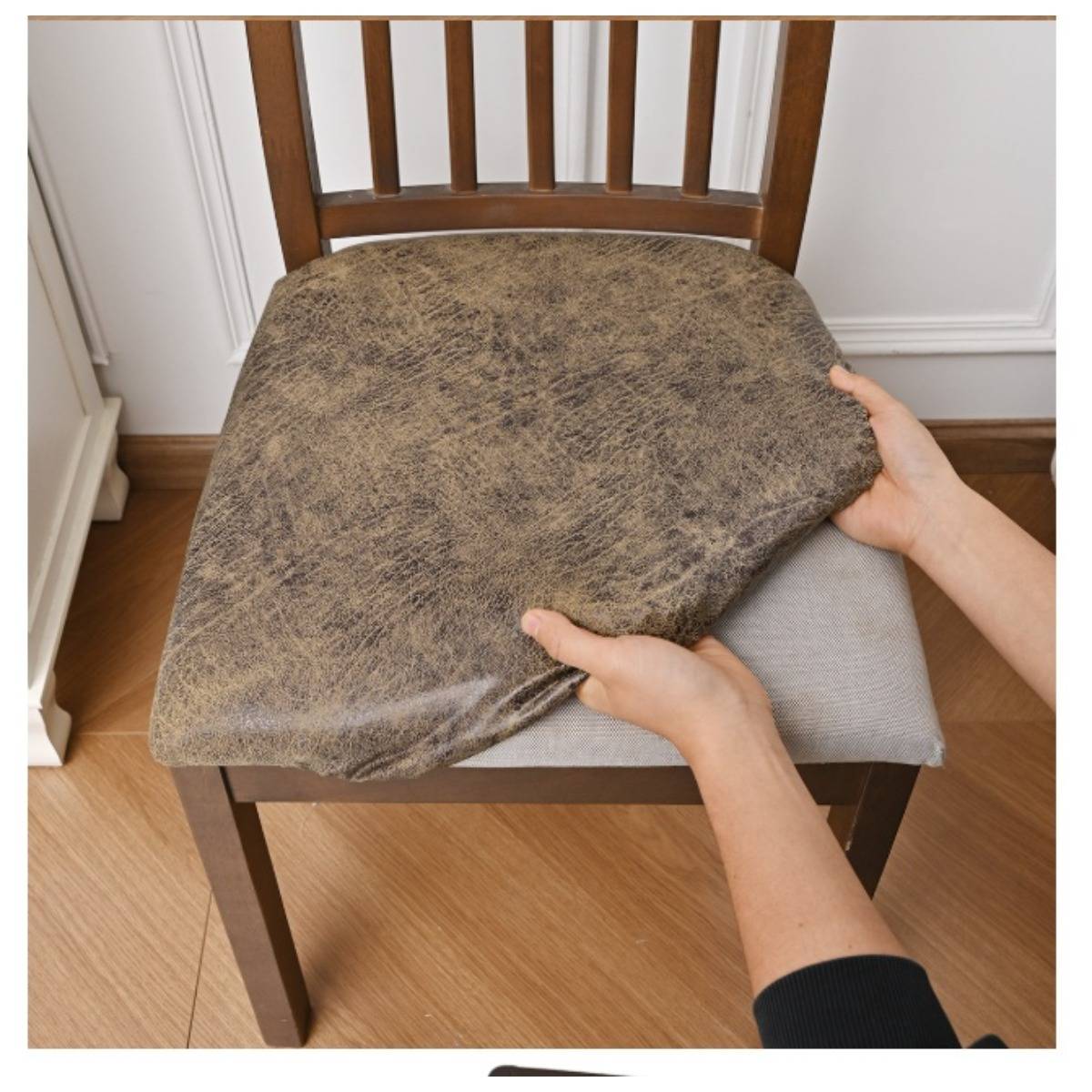Hände spannen einen Stuhlüberzug über einen Holzstuhl mit einem grauen Sitzkissen.
