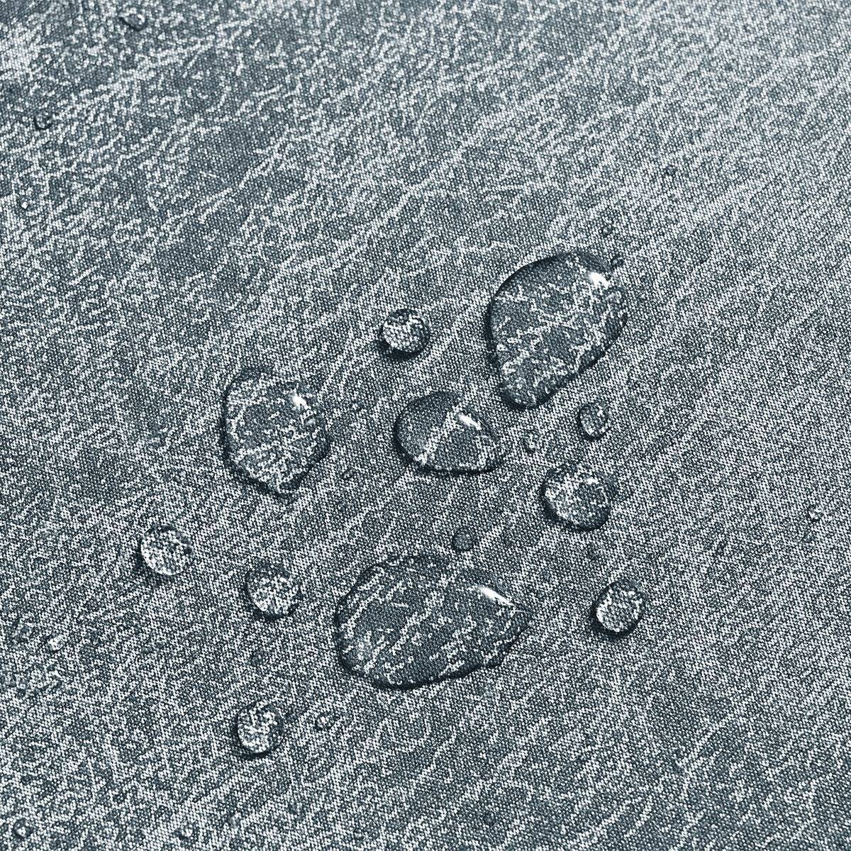 Nahaufnahme von Wassertropfen, die auf einem strukturierten grauen Stoff oder einer Oberfläche perlen.