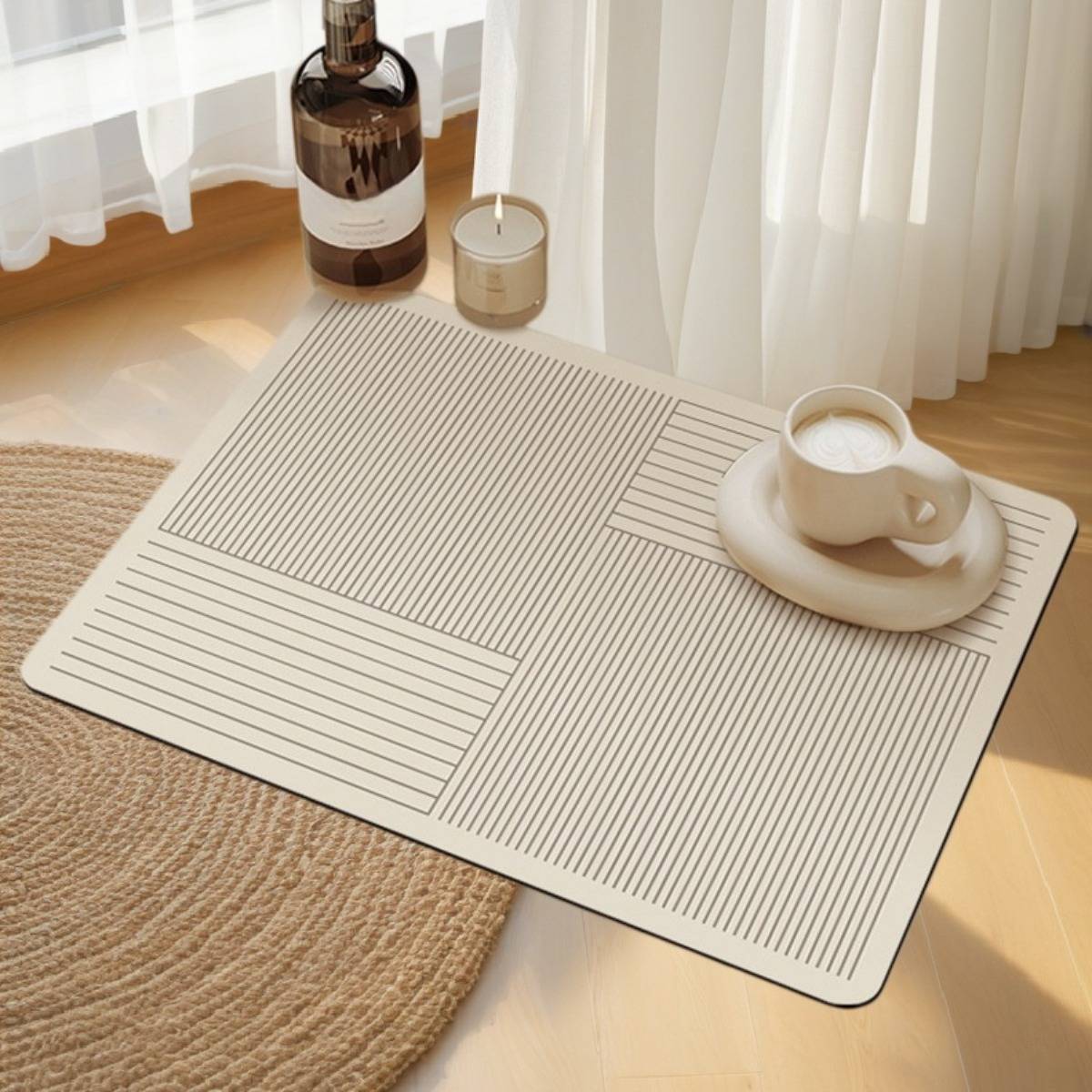 Minimalistischer Couchtisch mit einem cremefarbenen Tablett und Streifenmuster, auf dem eine Tasse mit Untertasse neben einer Flasche und einer Kerze im Sonnenlicht steht.