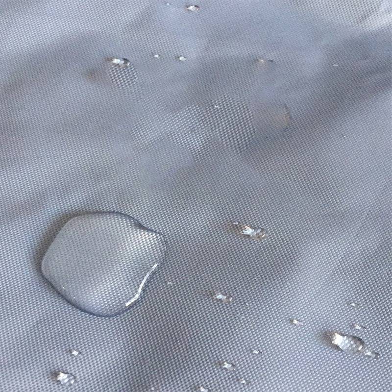 Nahaufnahme von Wassertropfen, die auf einem grauen strukturierten Stoff oder einer wasserdichten Oberfläche perlen.