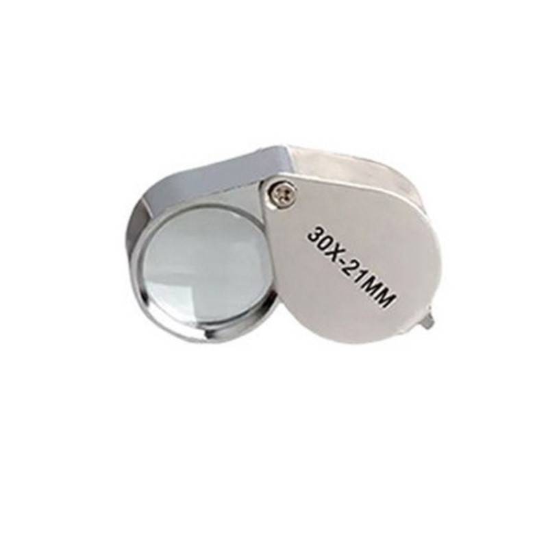 Nahaufnahme einer tragbaren Lupe mit eingeklapptem Metallschutz, beschriftet mit „30X-21MM".