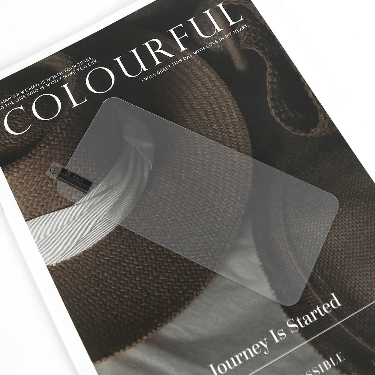 Ein Magazincover mit dem Titel „COLOURFUL" und dem Untertitel „Journey Is Started"", das eine durchsichtige Displayschutzfolie für Telefone auf einem dunklen gewebten Hintergrund zeigt.