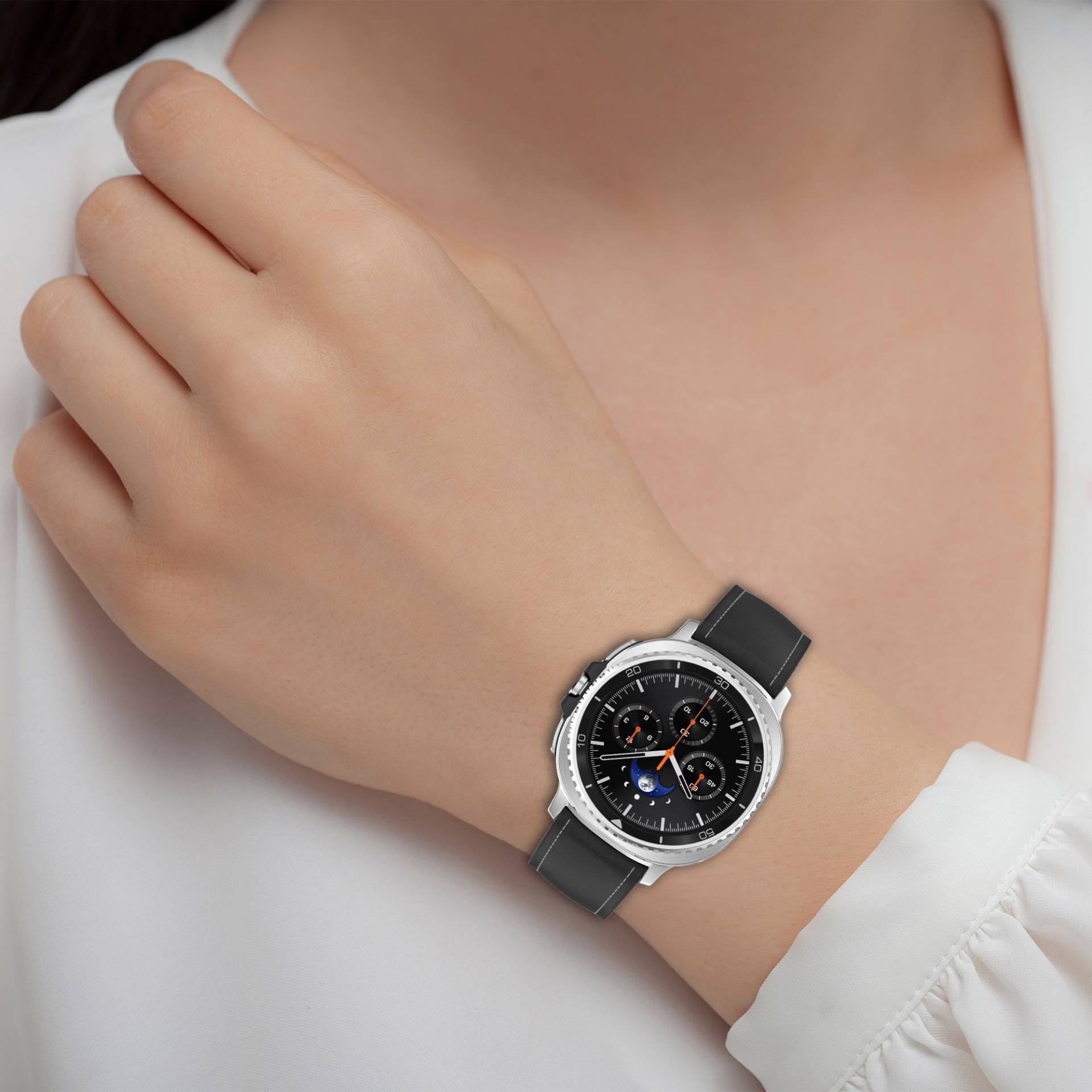 Nahaufnahme eines Handgelenks, das eine silberne analoge Chronographenuhr mit schwarzem Lederarmband an einer Person in einem weißen Hemd trägt.