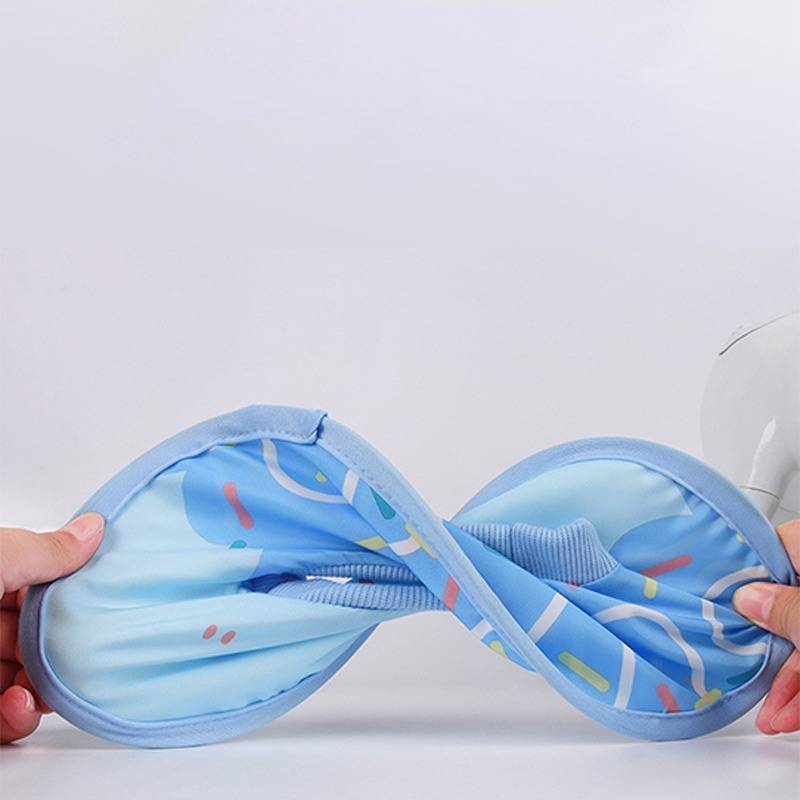 Hände dehnen ein blaues gemustertes elastisches Stoffband in eine Achterform gegen einen schlichten hellen Hintergrund.
