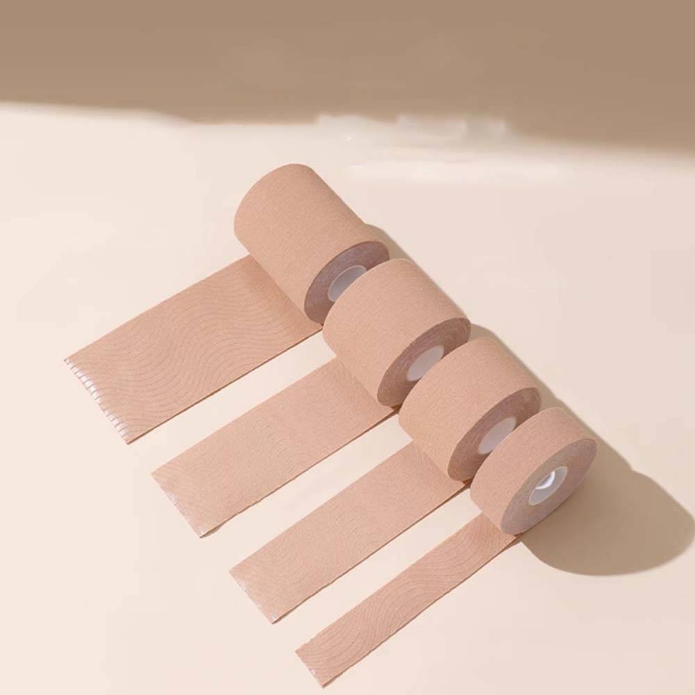 Vier beige Klebebandagen-Rollen mit ausgerollten Streifen auf hellem Hintergrund.