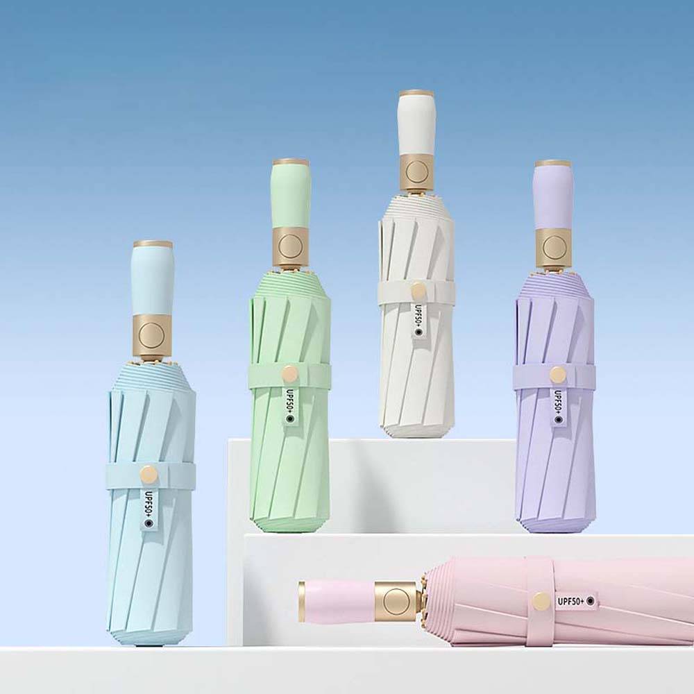 Regenschirme in Pastellfarben, die auf weißen Stufen vor einem blauen Hintergrund ausgestellt sind, mit einem rosa Regenschirm, der horizontal davor liegt.