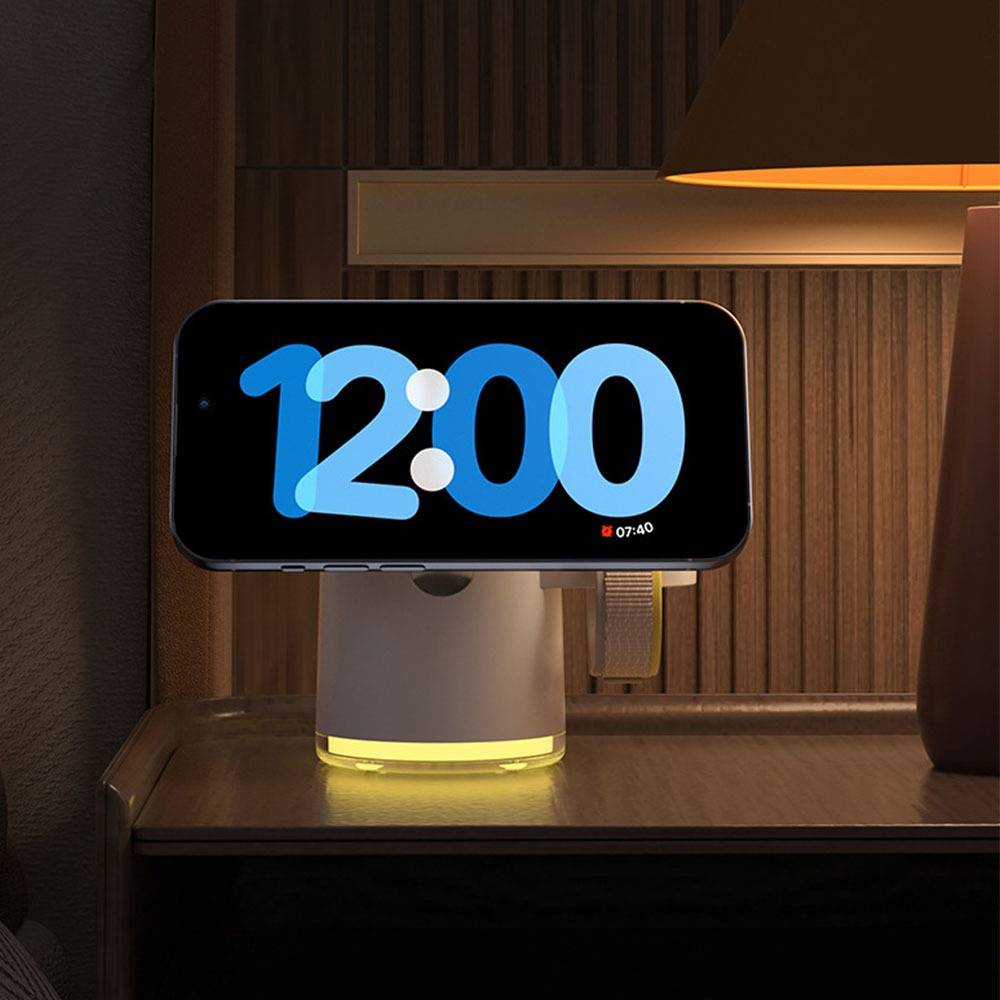 Eine digitale Nachttischuhr zeigt "12:00"" in großen blauen Zahlen auf einem schwarzen Display an und steht auf einem Nachttisch neben einer Lampe.