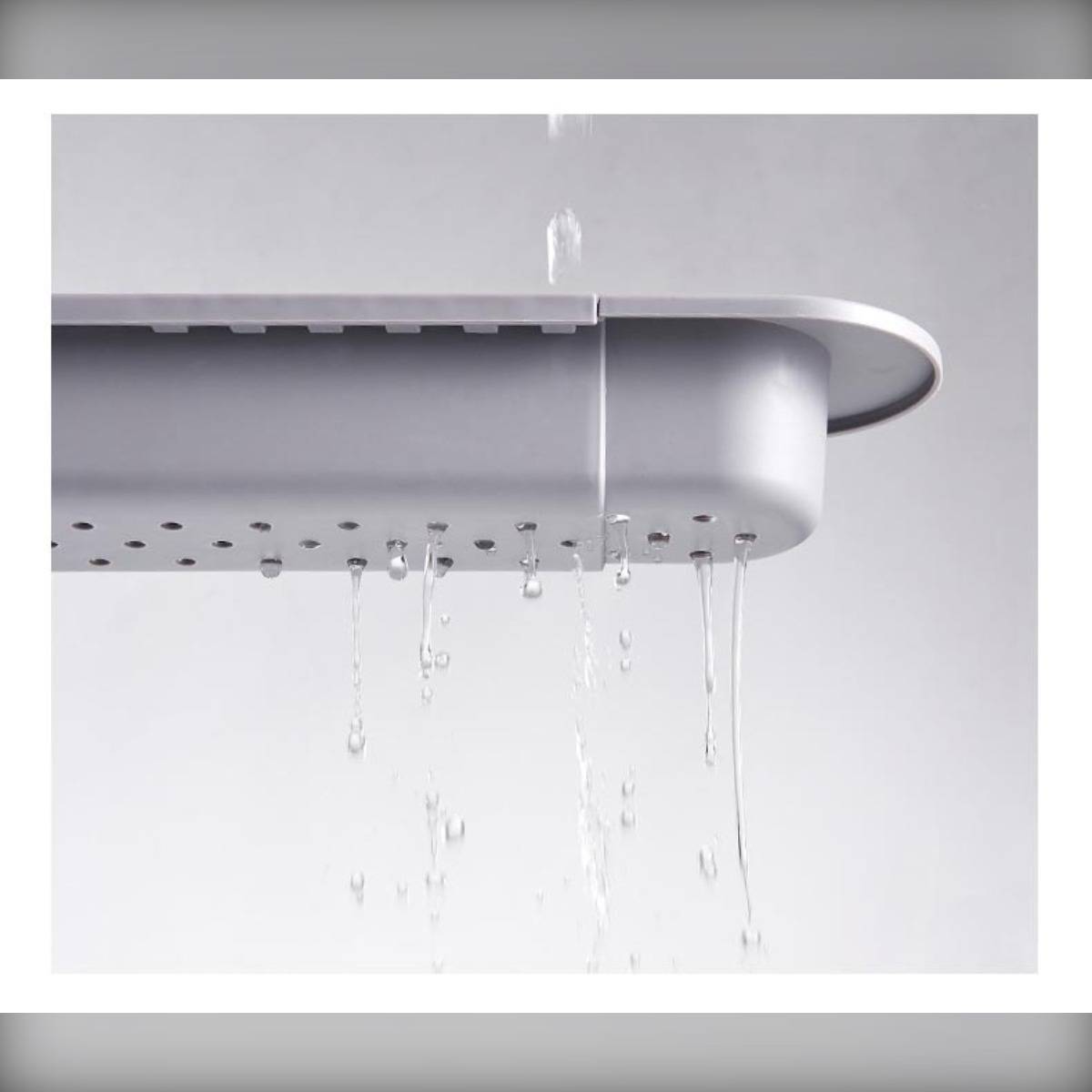 Nahaufnahme eines grauen, an der Wand montierten Regals oder Tabletts mit Wasser, das von seiner Unterseite tropft, was auf eine Entwässerungsfunktion hindeutet.