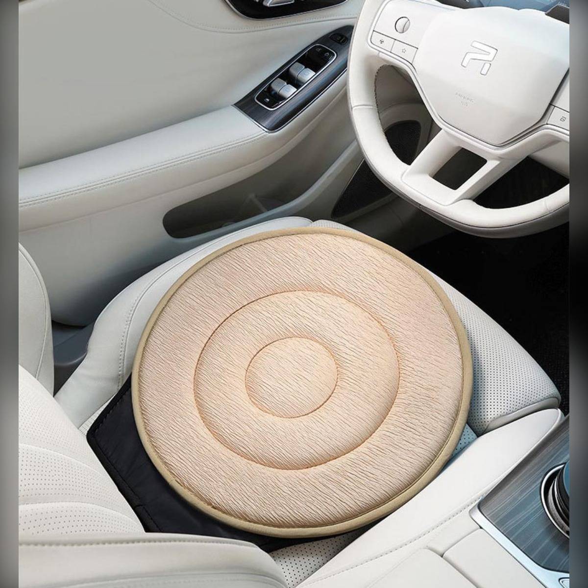 Helles Holz rundes Sitzkissen auf einem cremefarbenen Autositz neben dem Lenkrad, das Komfort und Stil zum vorderen Innenraum hinzufügt.