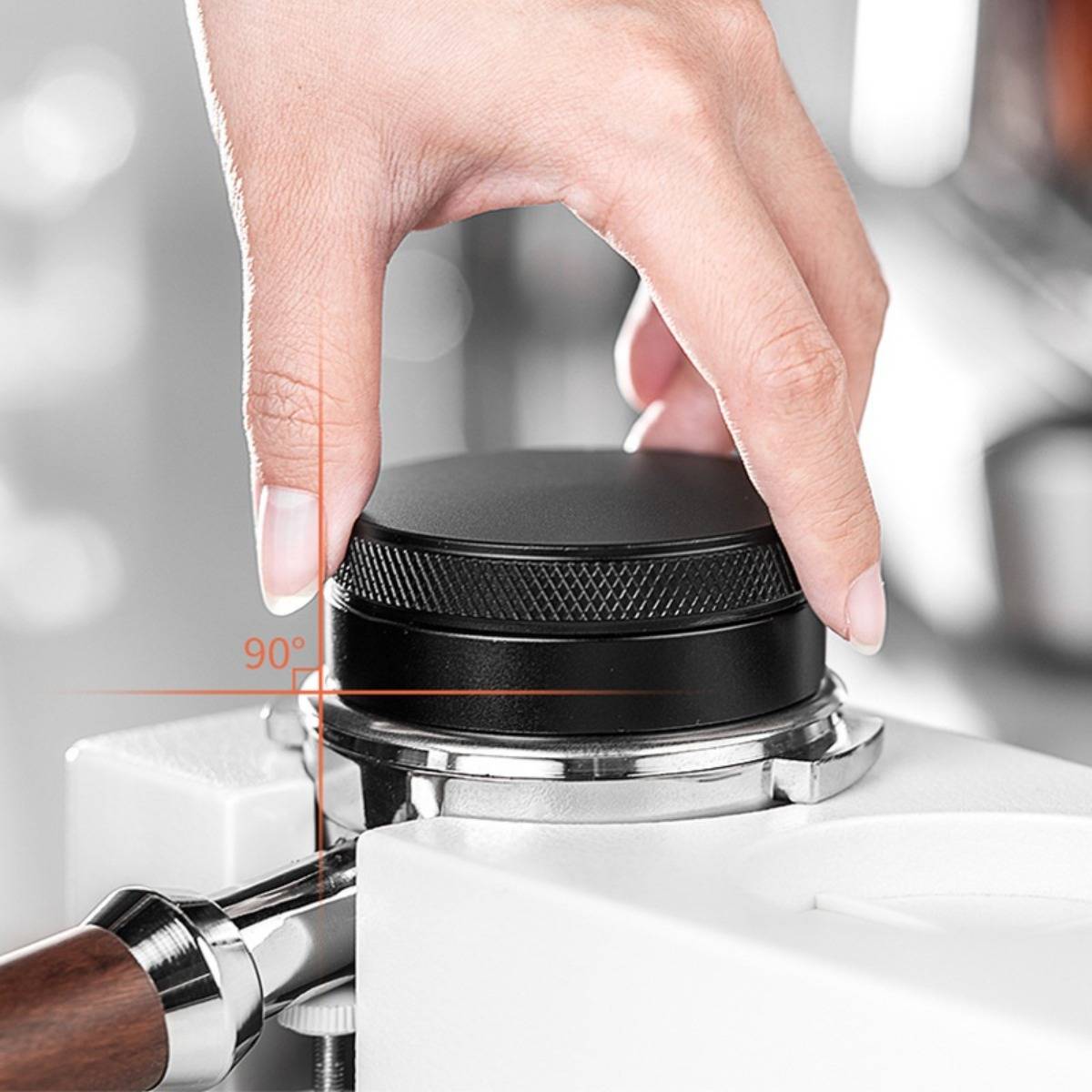 Hand, die einen schwarzen Einstellknopf auf dem Siebträger einer Espressomaschine in einem 90°-Winkel-Indikator platziert.