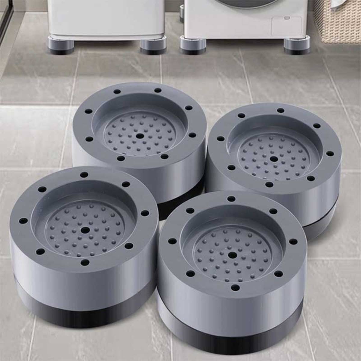 Vier runde graue Metallkomponenten mit perforierten Mitteln und Bolzenlöchern, angeordnet auf einem gefliesten Boden in einer Werkstatt oder einem Showroom.