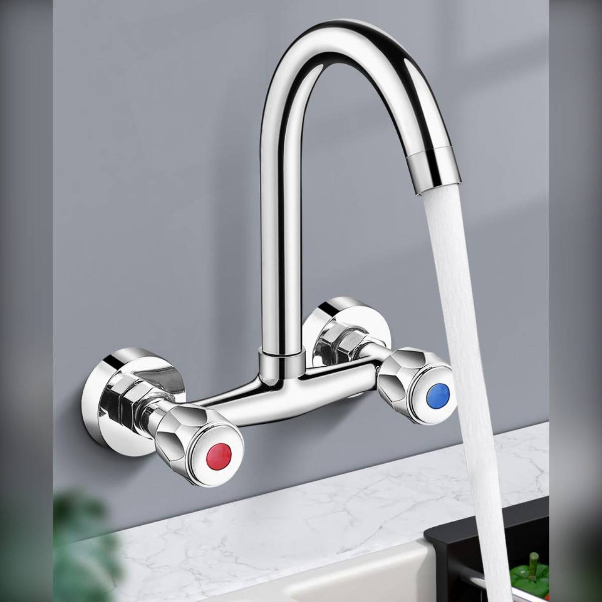 Wandmontierter Chromwasserhahn mit Wasser, das in ein Waschbecken fließt, mit roten und blauen Temperaturhebeln.