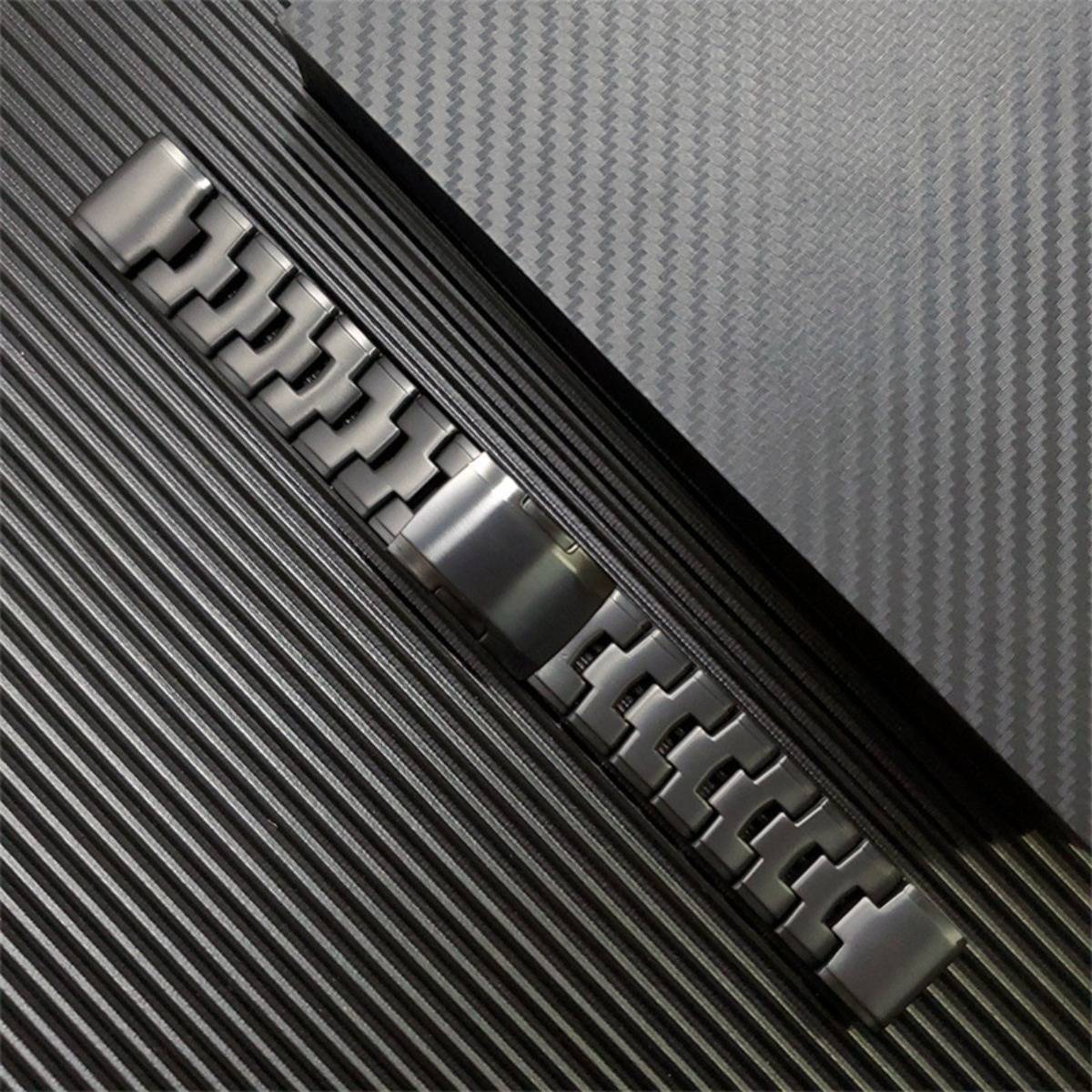 Nahaufnahme eines silbernen Metalluhrarmbandes und einer Schließe diagonal auf einem strukturierten schwarz-grauen Hintergrund.