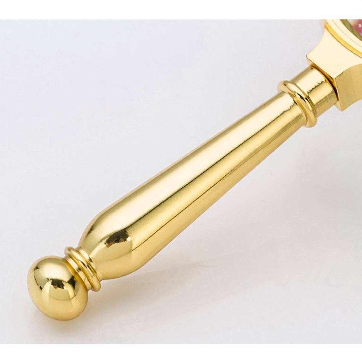 Nahaufnahme eines goldenen Zeremonialstabes oder Zepters mit einer abgerundeten Knopfspitze auf einem schlichten, hellen Hintergrund.