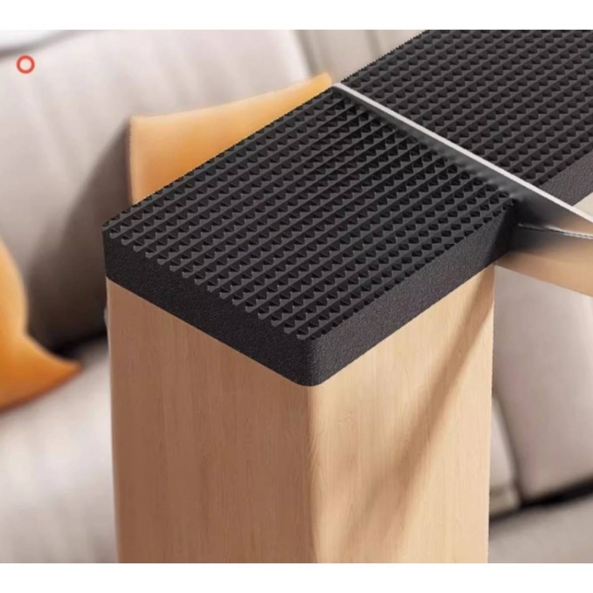 Nahaufnahme eines Holztisches mit schwarzer strukturierter Oberfläche, neben einem Sofa und Kissen in einem modernen Raum gezeigt.