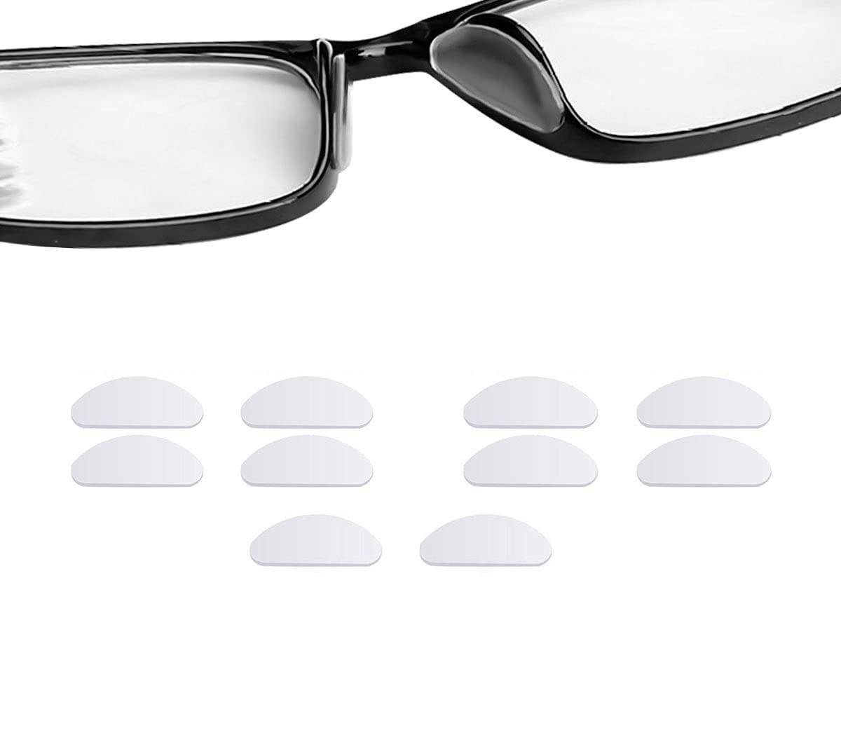 Schwarze Brille über acht weißen Klebepads für die Nase auf weißem Hintergrund.