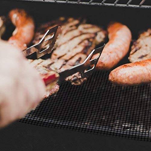 Würstchen und Aufschnitt grillen auf einem Drahtgitter, mit Grillzangen, die das Essen über einem offenen Grill umwenden.
