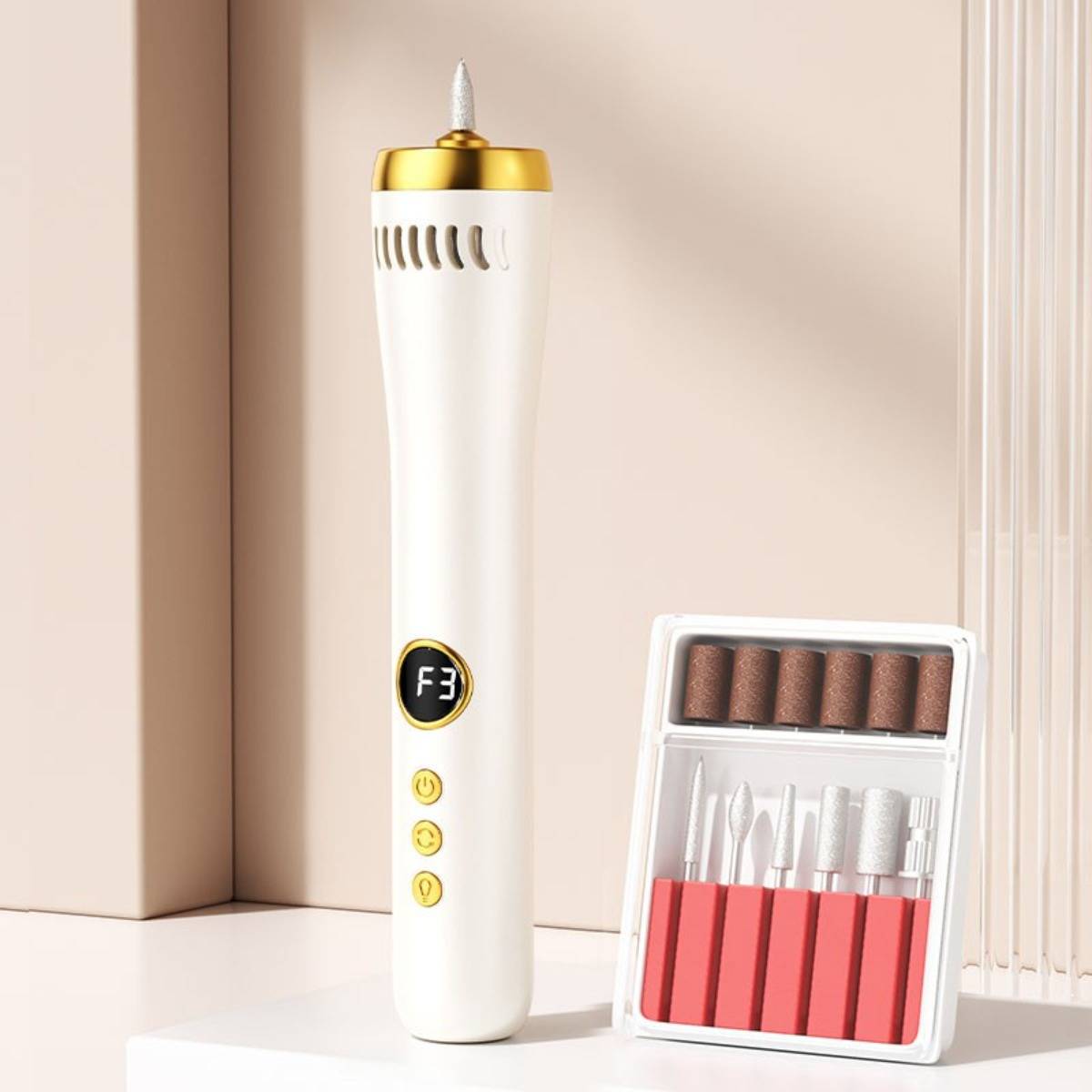 Weißer elektrischer Nagelbohrer mit goldenem Deckel und digitaler Anzeige neben einem Etui mit rotierenden Schleifbits auf einer Tischplatte.