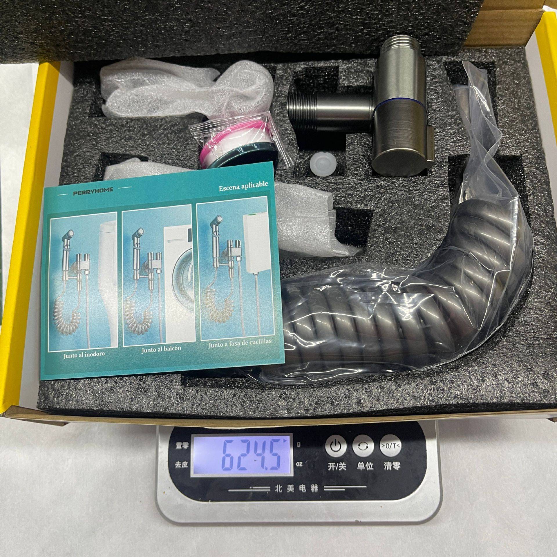 Verpackter Metall-Duschzubehörsatz mit Schlauch, Handbrause und Befestigung, angezeigt auf einer digitalen Waage mit Anzeige von 624,5 g.