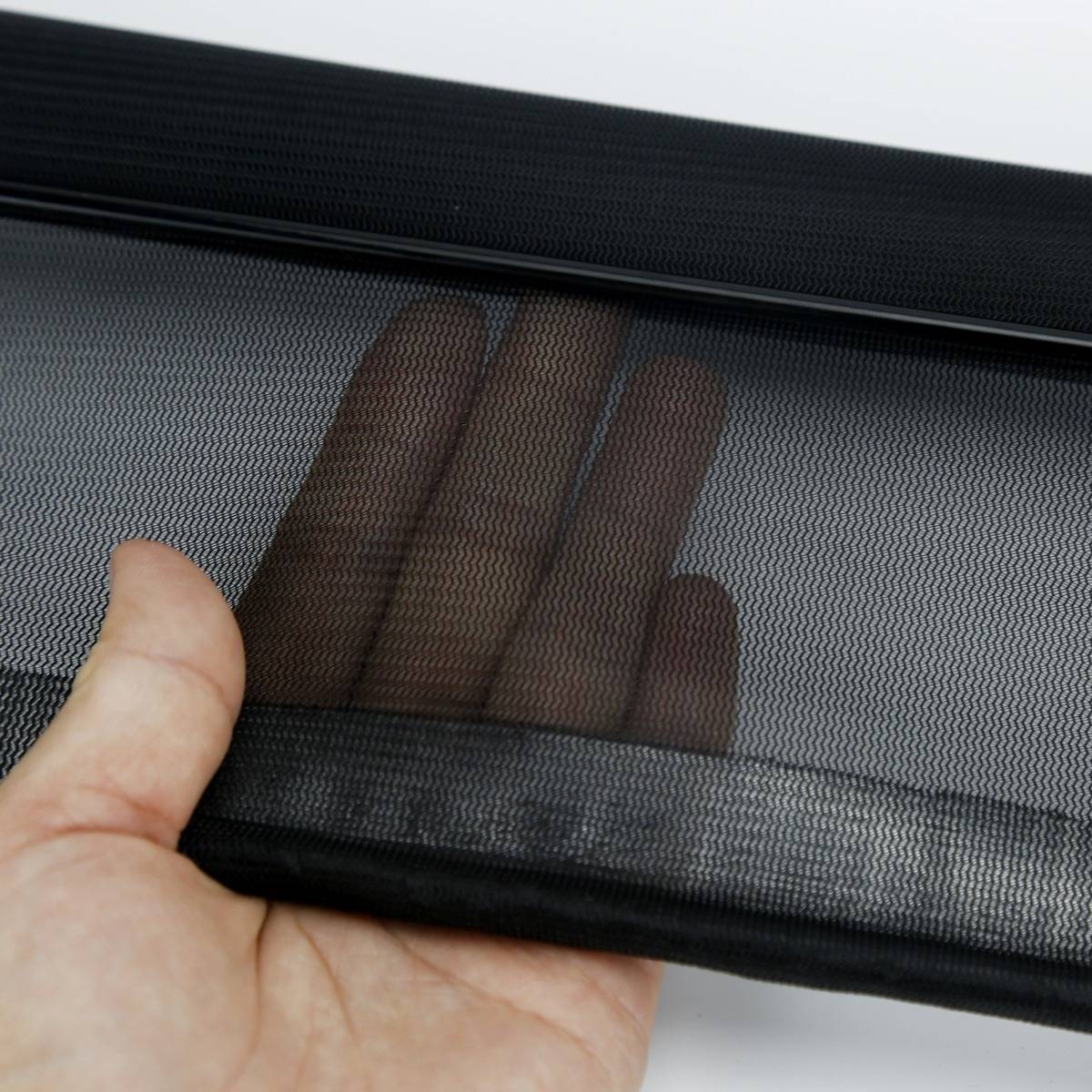 Eine Hand hält ein schwarzes Mesh-Fenstersieb oder eine Fensterblende und zeigt seine feine gewebte Textur und Flexibilität vor einem hellen Hintergrund.