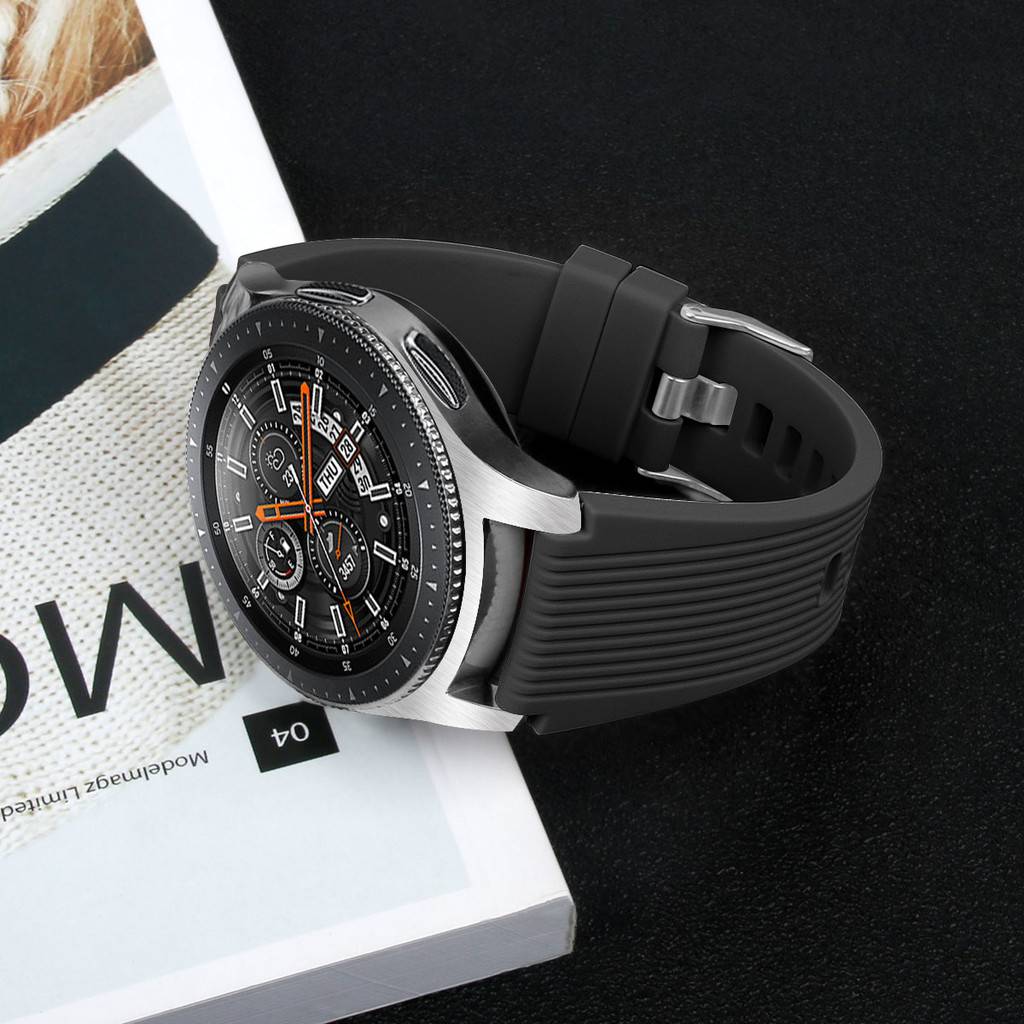 Schwarze analoge Smartwatch mit orangenen Akzenten und schwarzem Silikonarmband, gezeigt auf seiner weißen Verpackungsbox.